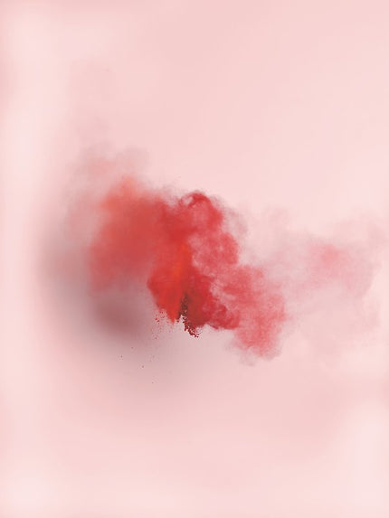 Fliegendes, rotes Farbpigment vor naturbeigem Hintergrund